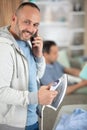 man ironing clothes while speaks on phone