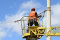 Man ironworker repairing trolleybus rigging standing on a truck mounted lift