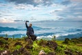 Man isolated taking selfie at hill top with amazing cloud layers in background