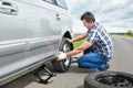 Man with jack changing a spare tire of car Royalty Free Stock Photo