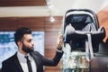 Man in a jacket choosing child car seat for newborn baby in shop supermarket. Royalty Free Stock Photo