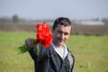 A man in a jacket on a field of tulips. Glade with tulips. A man is tearing tulips in a bouquet
