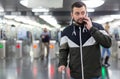Man in jacket with a mobile phone near turnstile in subway