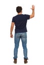 Man In Jeans And Blue T-shirt Is Standing With Arm Raised And Waving Hand. Rear View Royalty Free Stock Photo