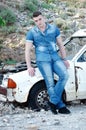 Man in jeans, sitting on an old damaged car