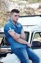 Man in jeans, sitting on an old damaged car Royalty Free Stock Photo