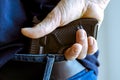 A person is hiding a handgun under the denim belt. Royalty Free Stock Photo