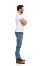 Young Man In Jeans And White T-shirt Is Standing With Arms Crossed And Looking Away. Side View Royalty Free Stock Photo