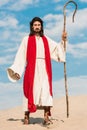 Man in jesus robe holding wooden cane and walking in desert Royalty Free Stock Photo