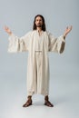 Man in jesus robe standing with outstretched hands on grey