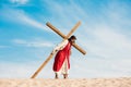 Man in jesus robe walking with wooden cross against sky in desert Royalty Free Stock Photo