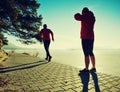 Man jogging at his girlfriend at river bank.  Hills with hot Sun Royalty Free Stock Photo