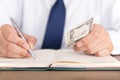 Man jot down things and some dollar banknotes in his notebook Royalty Free Stock Photo