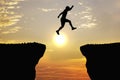 Man jump through the gap between hill.man jumping over cliff on sunset background,Business concept idea Royalty Free Stock Photo