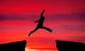 Man jump through the gap on sunset fiery background. Royalty Free Stock Photo