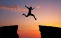 Man jumping across the gap from one rock to cling to the other.