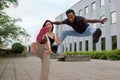 man jumping with a girl having one foot in the air, street style couple