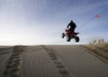 Man jumping his quad over a sand dune Royalty Free Stock Photo