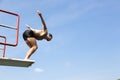 Man jumping off diving board at swimming pool