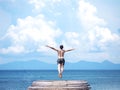 Man jumping off wooden bridge into blue sea. Royalty Free Stock Photo