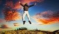 Man jumping out of happiness and emotions in front of a dramatic cloudy sunset Royalty Free Stock Photo