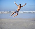 Man, jumping and portrait for happiness at beach, outdoor fun and happy in summer on vacation. Young person, playing and Royalty Free Stock Photo