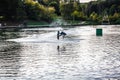 Man jumping on the wakeboard having healthy summertime on the river. Male wakeboarder jumps over spray on pond in park Royalty Free Stock Photo