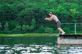 The man jumps and dives into the river in the forest background