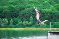 The man jumps and dives into the river in the forest background