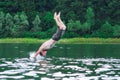 The man jumps and dives into the river in the forest background