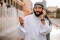 Man in kaffiyeh and thobe with a phone in hands