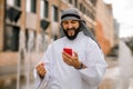 Man in kaffiyeh and thobe with a phone in hands