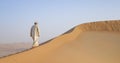 Man in kandura in a desert at sunrise