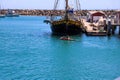 A man on a kayak sailing through the harbor surrounded by vast deep blue ocean water and ships, boats and yachts