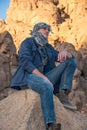 Man in a keffiyeh sitting on a rock in the desert