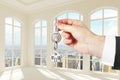 Man with key in hand in modern sunny white room with city view