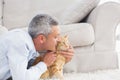 Man kissing cat by sofa at home Royalty Free Stock Photo