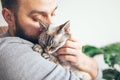 Man Is Kissing And Cuddling His Sweet And Cute Looking Devon Rex Cat. Kitten Feels Happy To Be With Its Owner.  Kitty Sits In