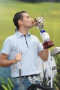 man kissing golf trophy