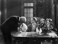 Man kissing hand of woman sitting at desk