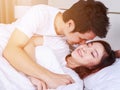 Man is kissing his beautiful smiling wife in cheek on bed