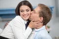 Man kissing his smiling wife on cheek. Cheerful beautiful woman with her eyes closed being kissed by her husband. Close