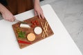 A man in the kitchen cuts cheese on a board on a white table. Different types of cheese Royalty Free Stock Photo