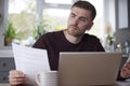 Man In Kitchen At Home Looking At Domestic Bills  With Laptop And Calculator Royalty Free Stock Photo