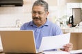 Man in kitchen with laptop and paperwork Royalty Free Stock Photo