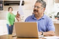 Man in kitchen with laptop and paperwork Royalty Free Stock Photo