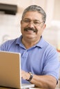 Man in kitchen with laptop smiling Royalty Free Stock Photo