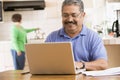 Man in kitchen with laptop smiling Royalty Free Stock Photo