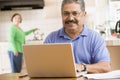 Man in kitchen with laptop smiling Royalty Free Stock Photo