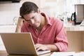 Man in kitchen using laptop frowning Royalty Free Stock Photo